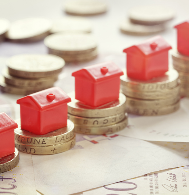 real-estate-growth red toy homes stacked on top of coins