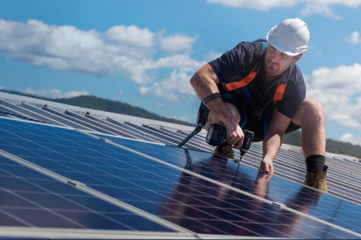 A solar technician installing solar panels on a roof.