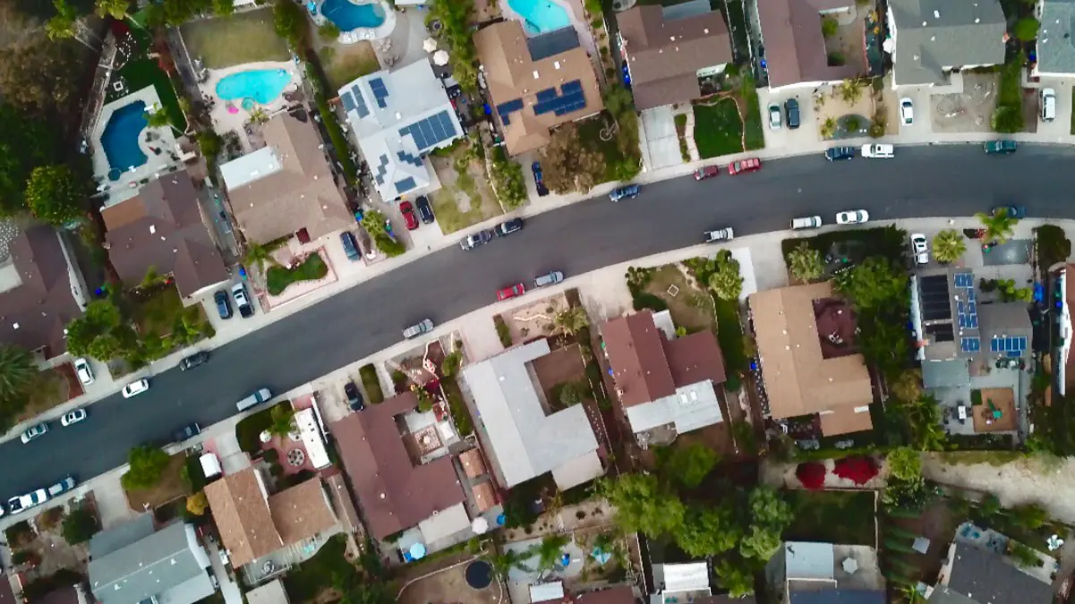 Drone view photo of residential neighborhood with pools and solar panels