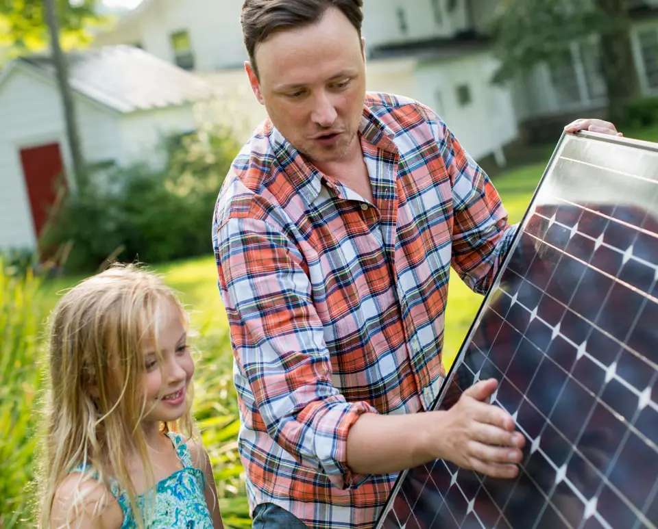 Man reviewing a solar panel with his young daughter
