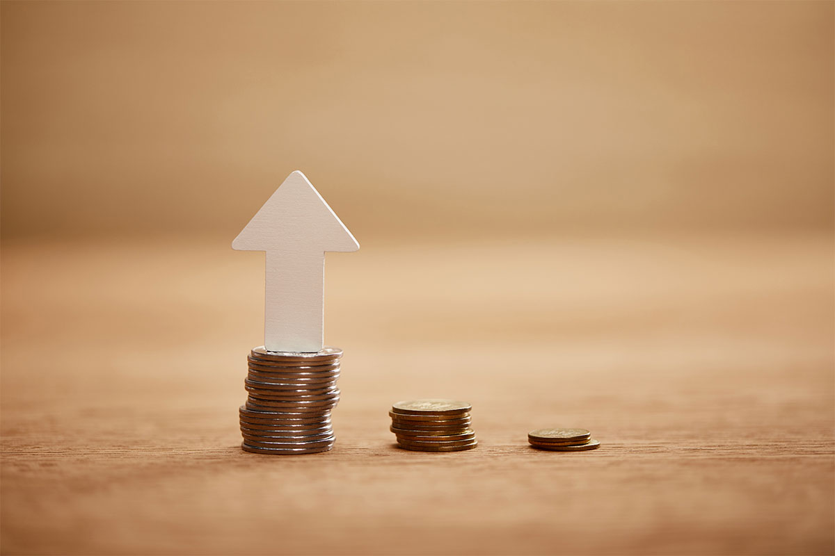 Coin stacking on top of each to other to create a bar graph with a white arrow pointing up