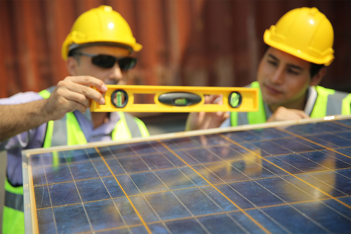 Two solar panel contractors checking the leveling on a new install