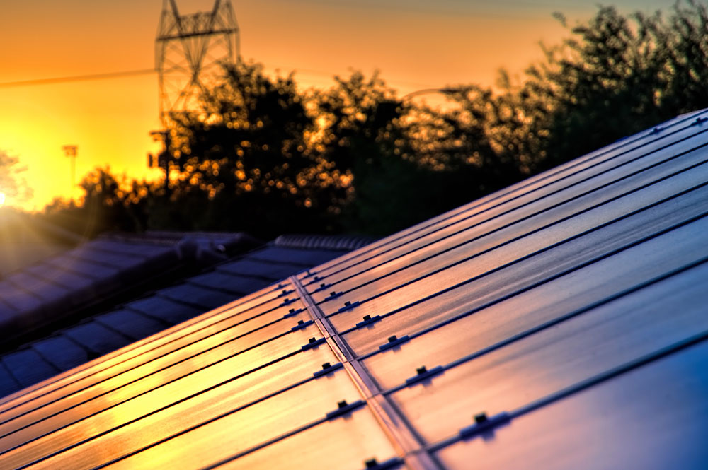 Rooftop solar panels in front of a skyline during the evening