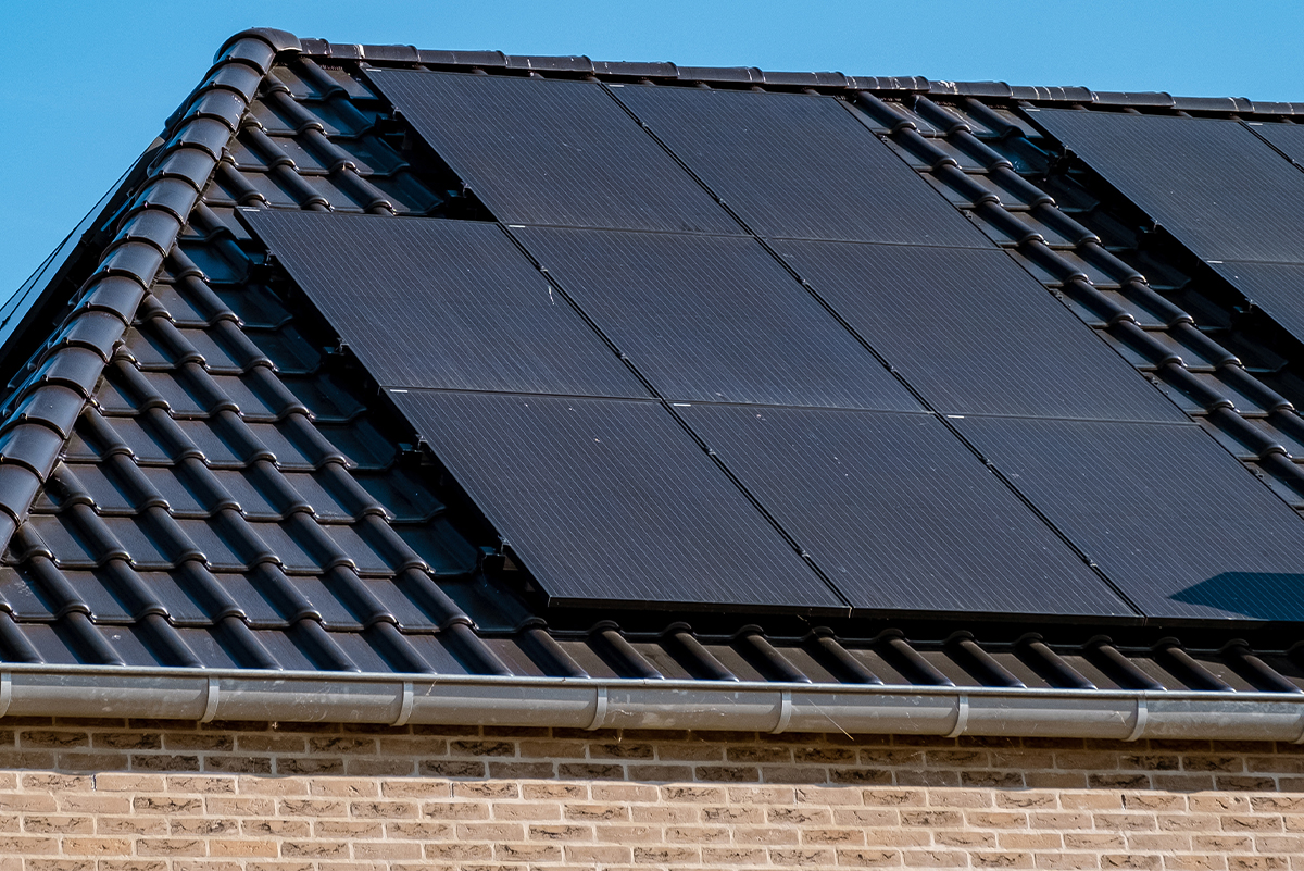 Newly built, brick home with solar panels attached on the roof against a sunny sky