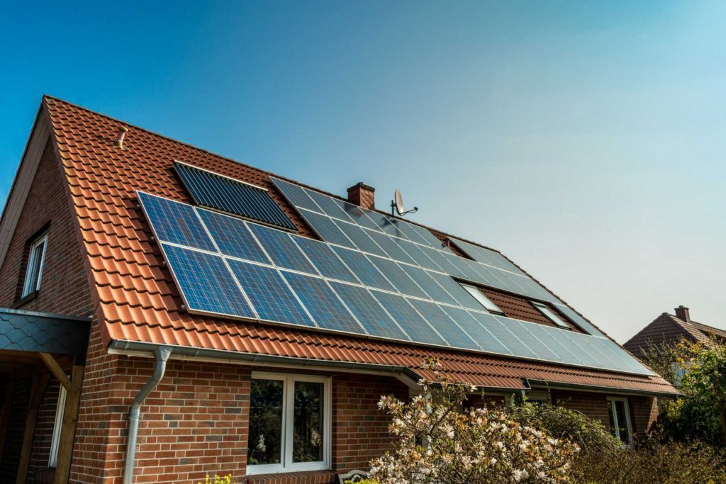 Brick house with shrubbery and a tiled roof covered in solar panels