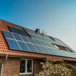 Brick house with shrubbery and a tiled roof covered in solar panels