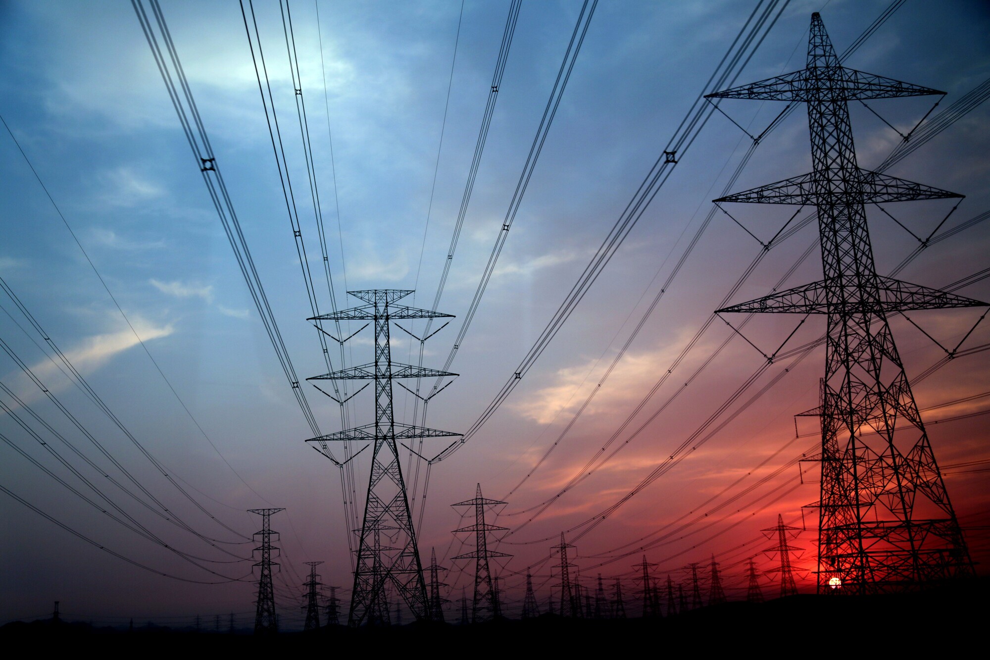 Power lines under an overcast red and blue sky